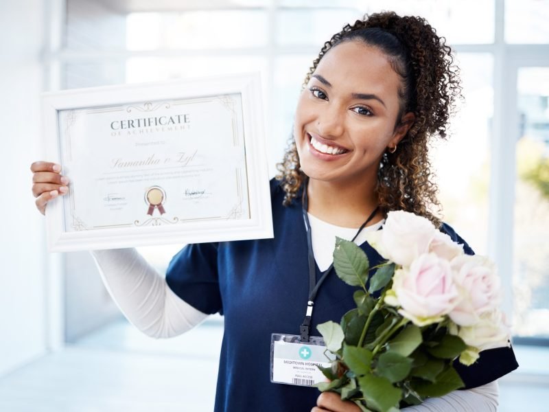 Certificate, rose and portrait with a black woman graduate in the hospital, proud of her achievemen