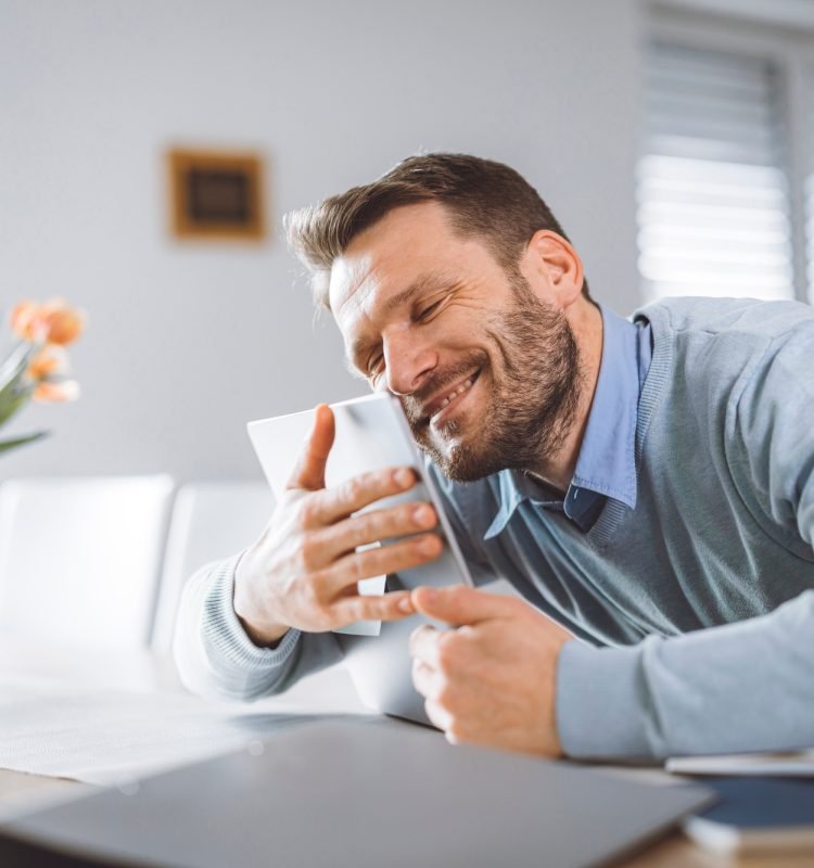 Excited man full of energy sitting behind laptop with big smile on his face. Overly happy person loo
